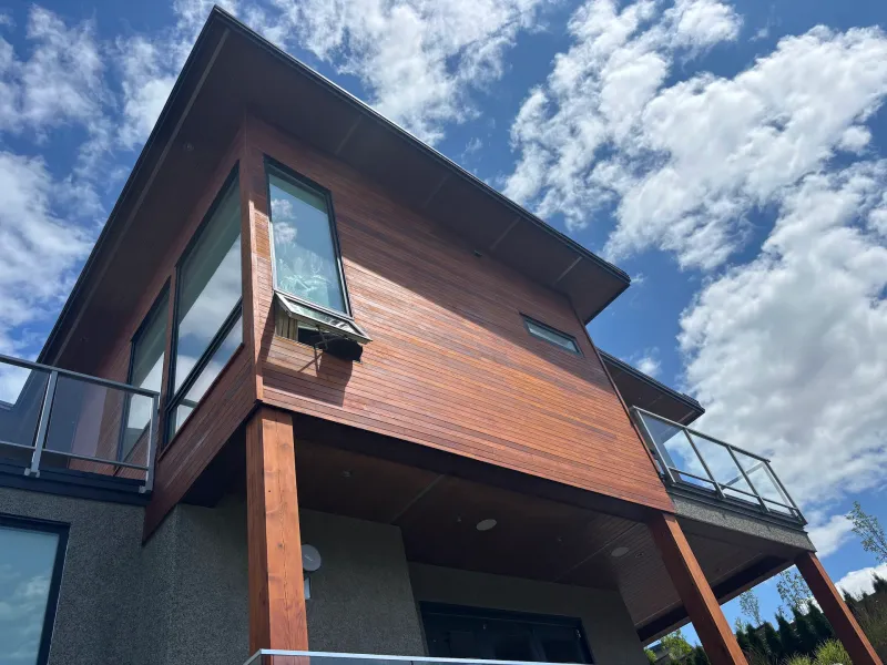 After: Front corner elevation of house with refinished siding, large windows and balcony over entry, Whistler, BC