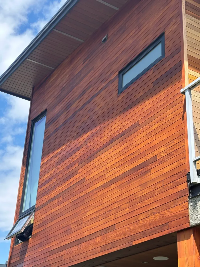After: Side elevation wall with refinished siding and two narrow windows under angled roofline, Whistler, BC