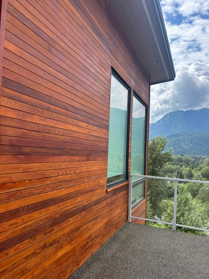 After: Side wall with refinished siding and two tall windows opening onto a balcony overlooking mountains, Whistler, BC