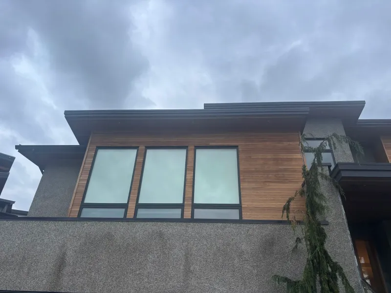 Before: Upper section of house front with three large windows framed by siding and stucco, Whistler, BC
