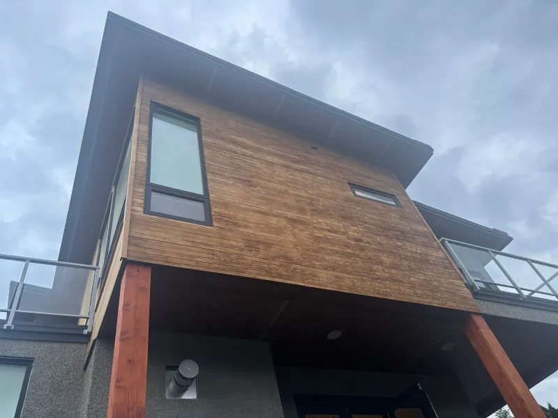 Before: Corner elevation showing siding, balcony railing and support posts over entry, Whistler, BC