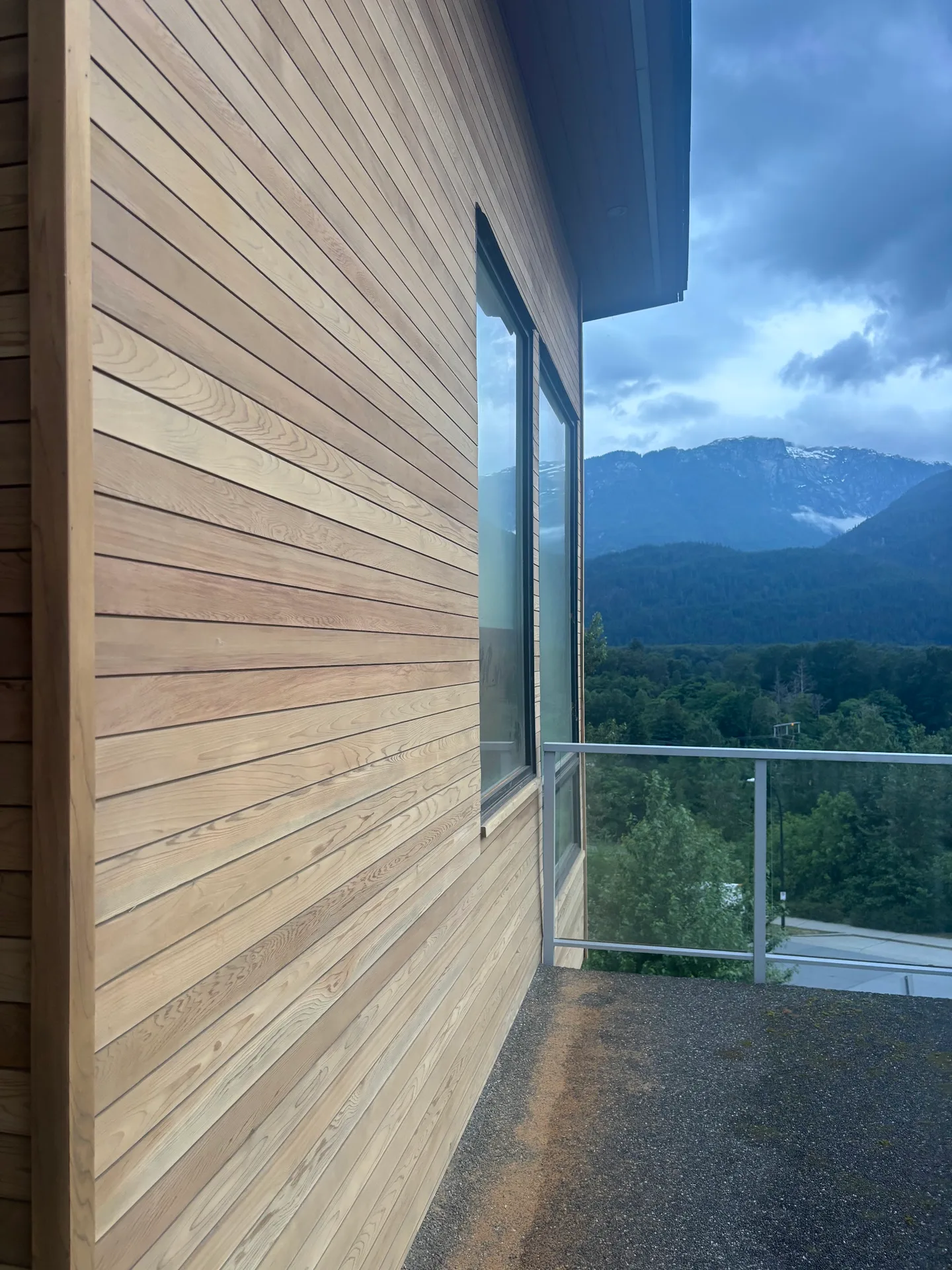 Before: Side wall with siding and tall window opening onto a balcony overlooking mountains, Whistler, BC