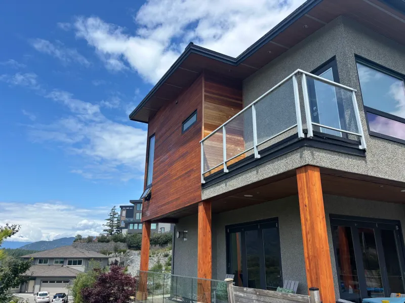 Before: Front corner of house showing siding accent, balcony railing and support posts above entry, Whistler, BC