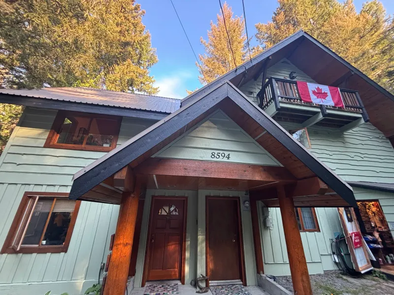 After: Front entry elevation with dual doors, gable roof, and balcony after painting, Whistler, BC