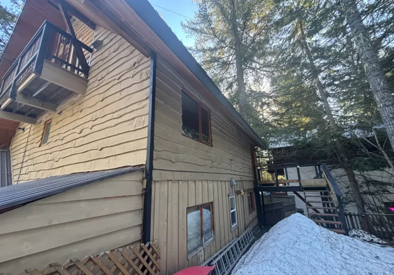 Before: Side elevation of house with lap siding, windows, and balcony before painting, Whistler, BC