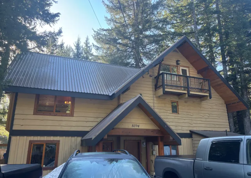 Before: Front elevation of house with gabled roofline, balcony, and entry before painting, Whistler, BC
