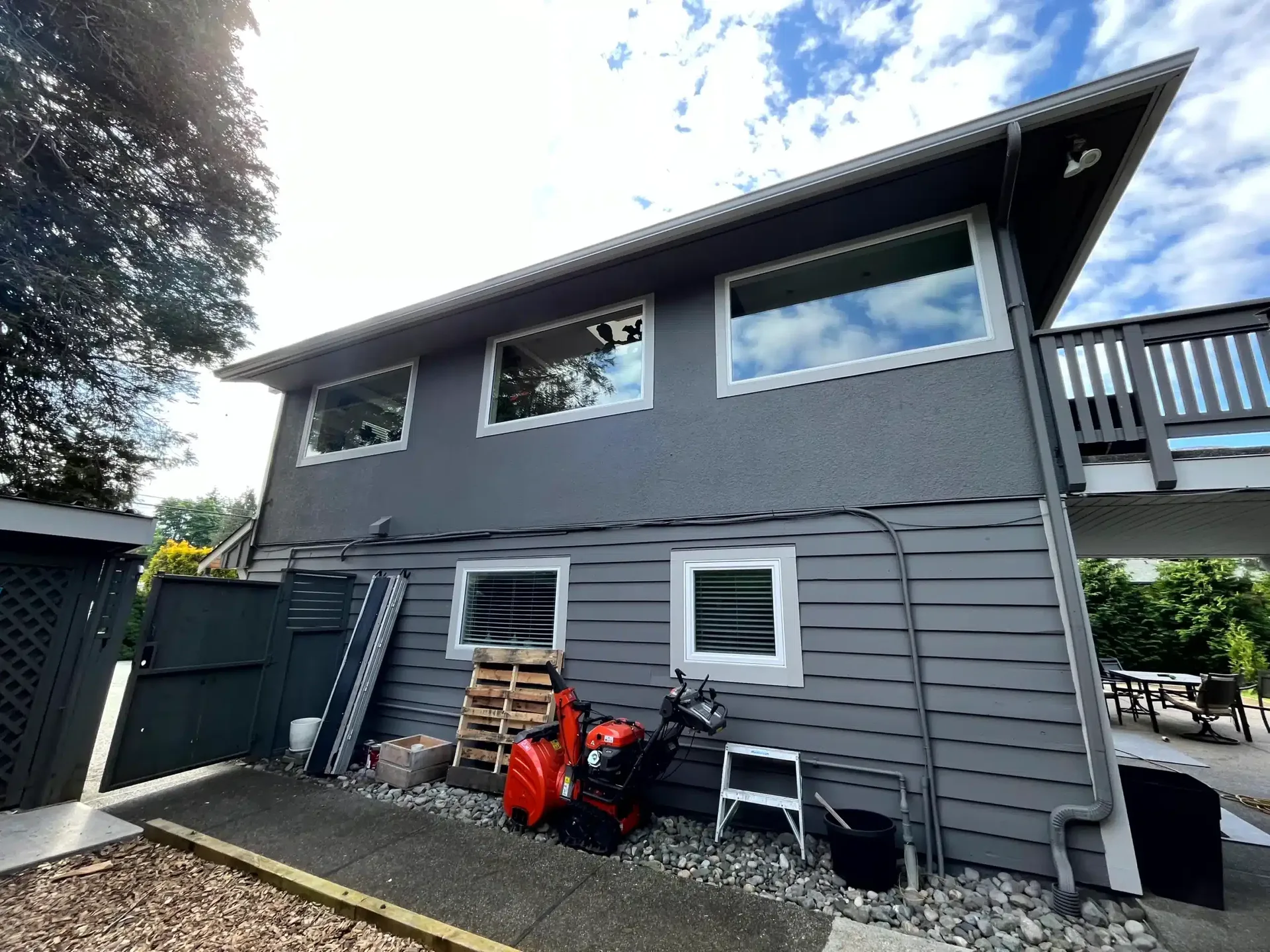 Repainted home with dark grey siding and stone garage base