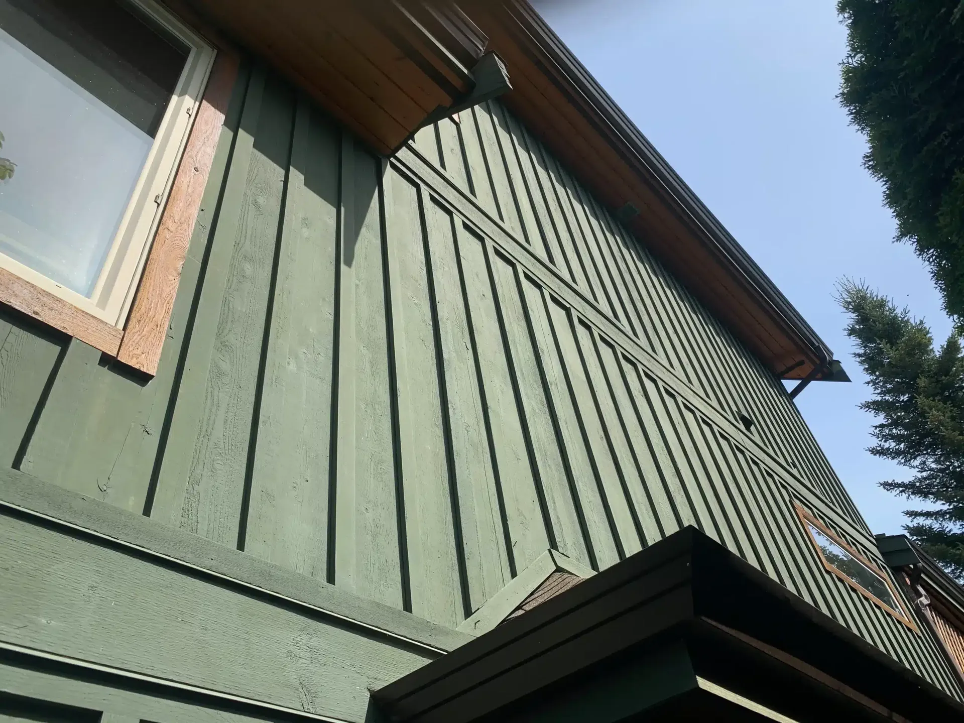 Newly painted green vertical board-and-batten siding