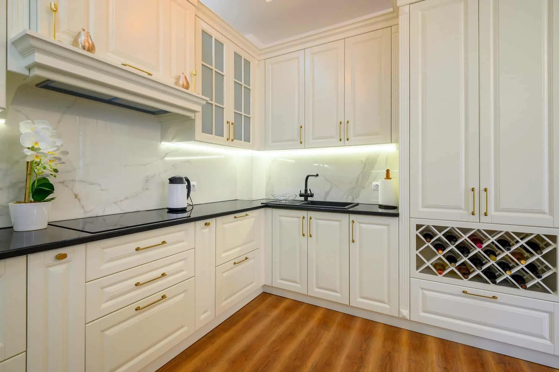 Modern kitchen with freshly painted white cabinets, black countertops and gold hardware