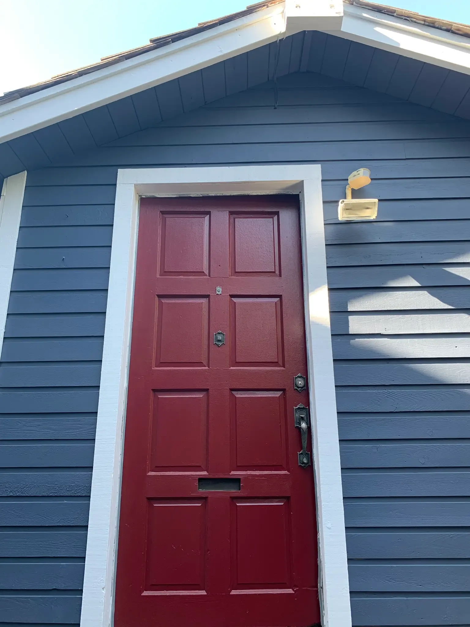 After — Red shed door on navy siding, Brackendale Squamish BC