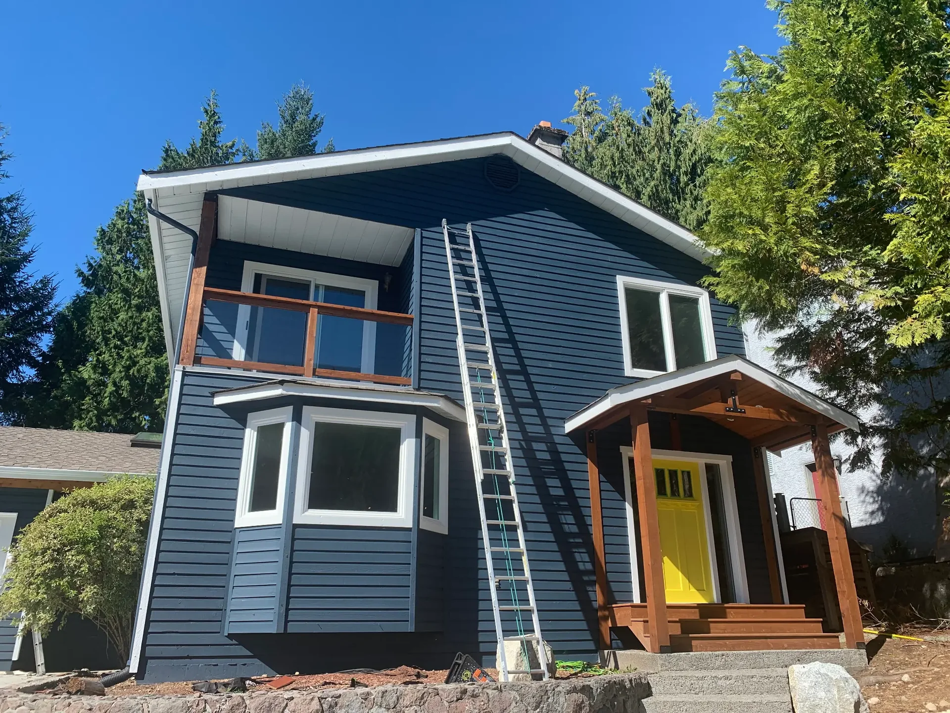 Exterior house painters working on navy siding in Squamish BC — Colour Craft Painting