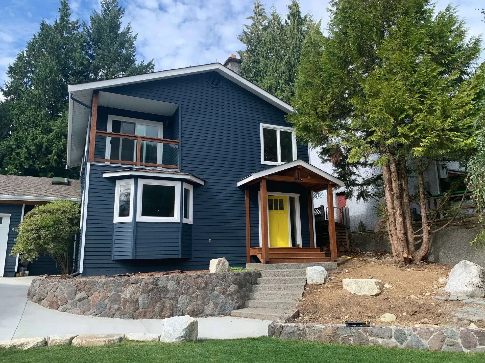 Completed exterior repaint — navy siding and yellow door, Squamish BC exterior painters