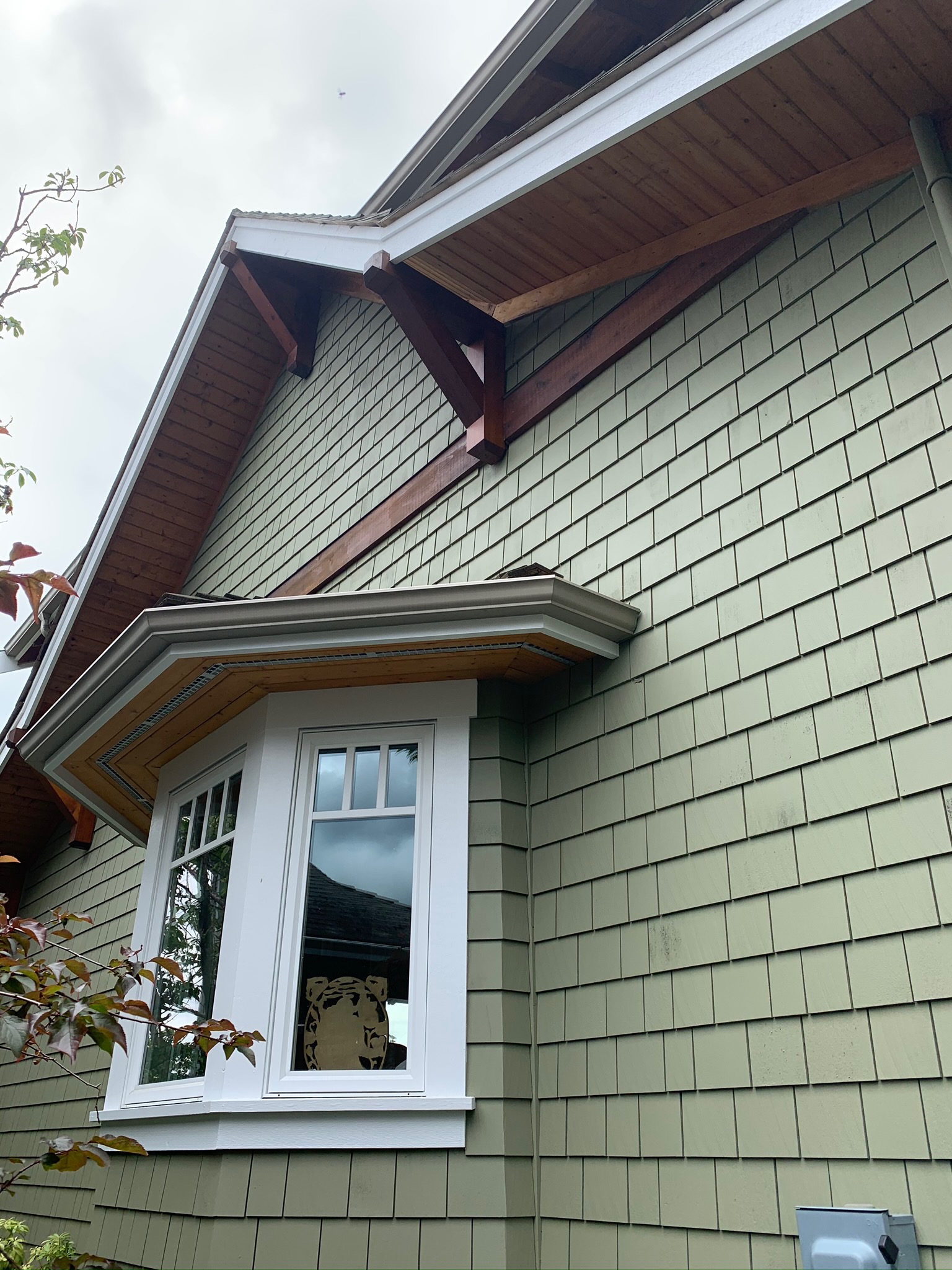 Completed green siding, white trim, and natural wood detail at James’s North Vancouver home