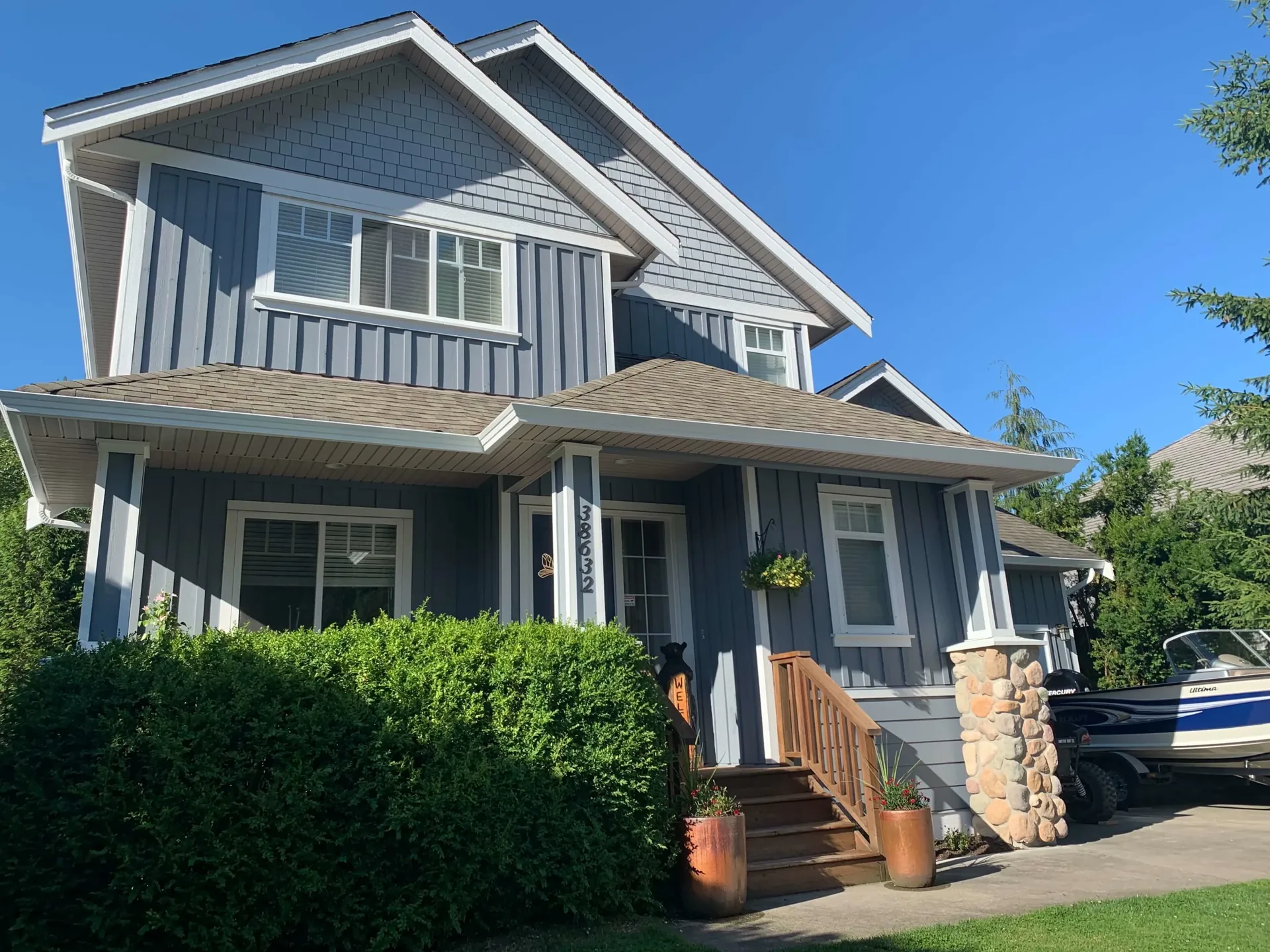 Two-storey Squamish home with blue siding, white trim and stone accents — exterior house painting by Colour Craft