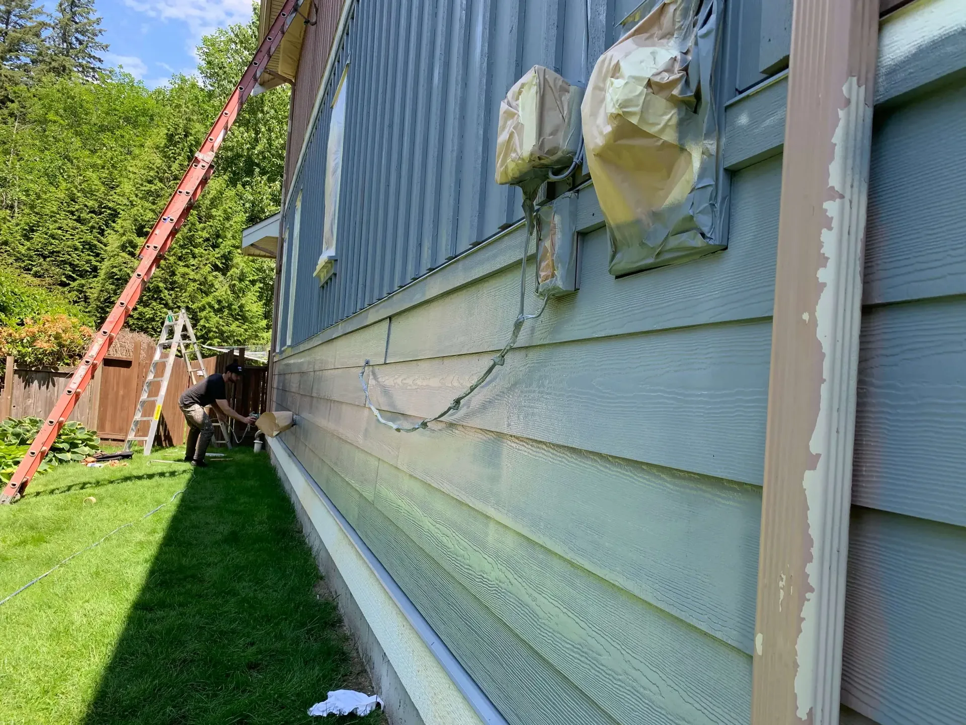 In progress — lower siding spray application, Squamish BC exterior painters