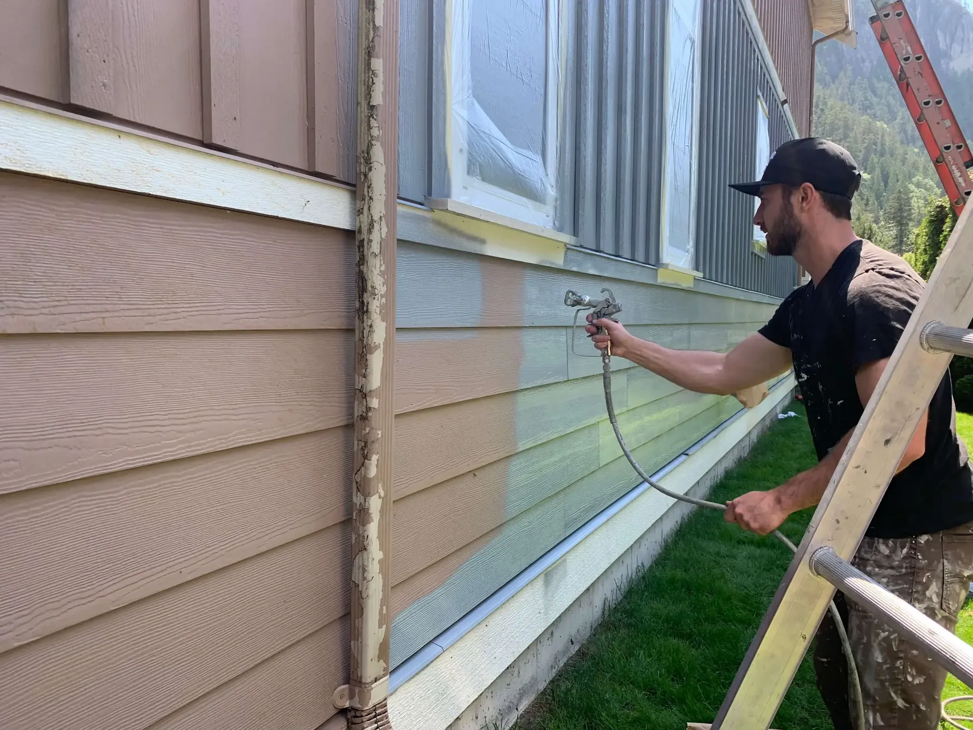 Exterior painting in progress — spray application, Valley Cliff Squamish BC